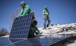 Workers installing solar panels, which will now become more expensive